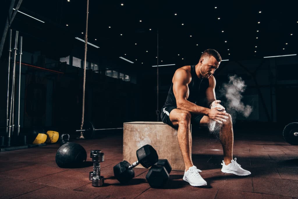 Athletic man at gym sitting on wooden box.